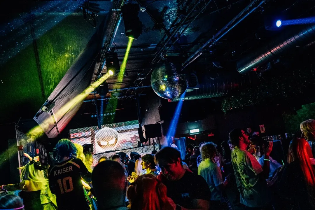 A crowded anime disco dance floor in Belfast under blue and pink lights